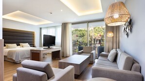 Una habitación de hotel moderna con cama, sofá, televisión y un balcón con vistas.