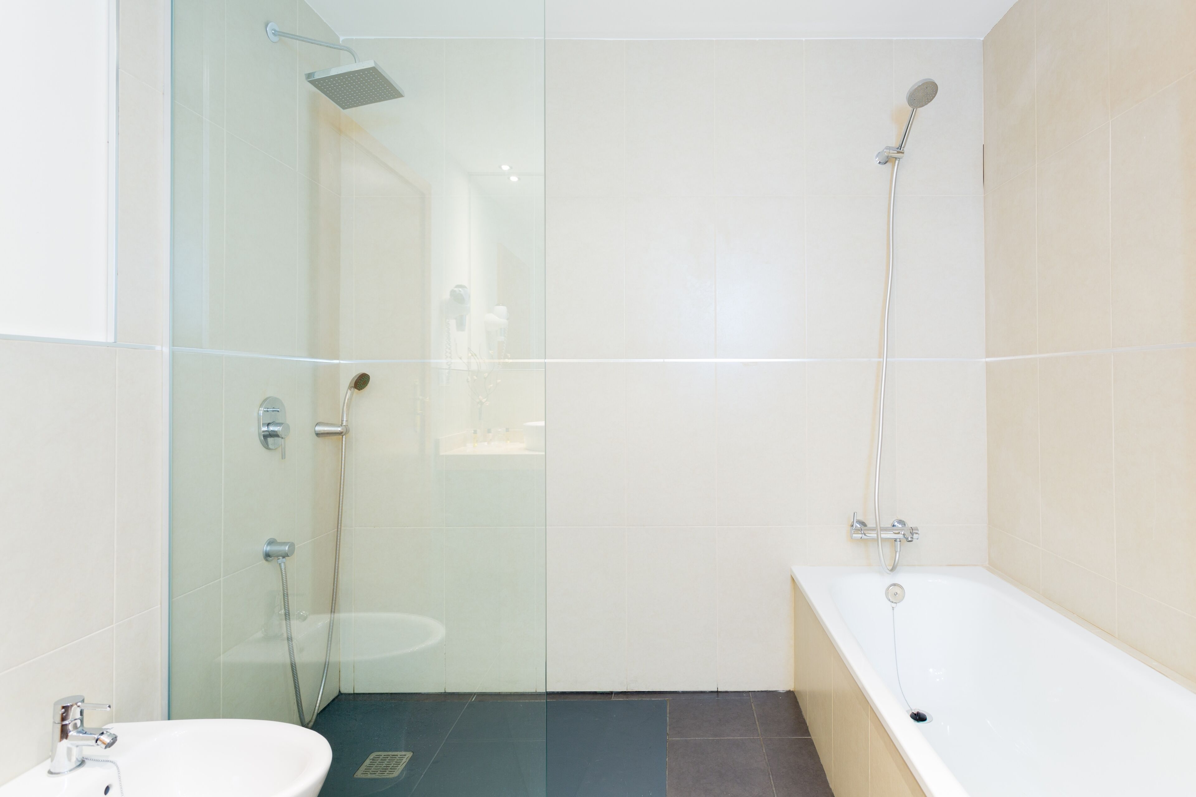 A modern bathroom with a glass shower enclosure, a bathtub, and a sink.