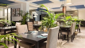 Un comedor moderno con varias mesas, sillas y lámparas colgantes.