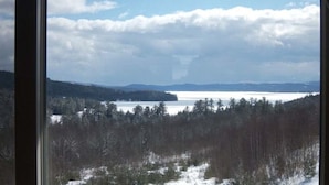 A view from a window overlooking a snowy landscape with a lake and forested hills. - Coppertoppe Inn and Retreat Center (Hebron)