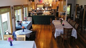 A cozy restaurant with wooden flooring, a central bar area, and tables with floral centerpieces. - Coppertoppe Inn and Retreat Center (Hebron)