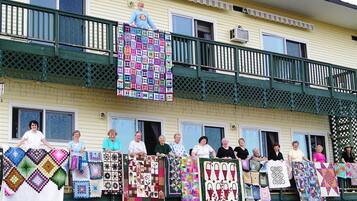 A building with a green balcony and a group of people holding quilts.