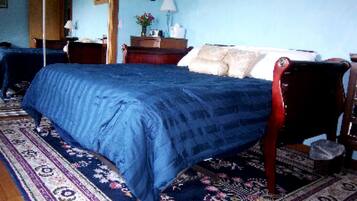A bedroom with a bed, a nightstand, a dresser, and a window.