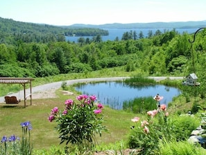 A lakeside view with a gazebo, a pond, and a small house.