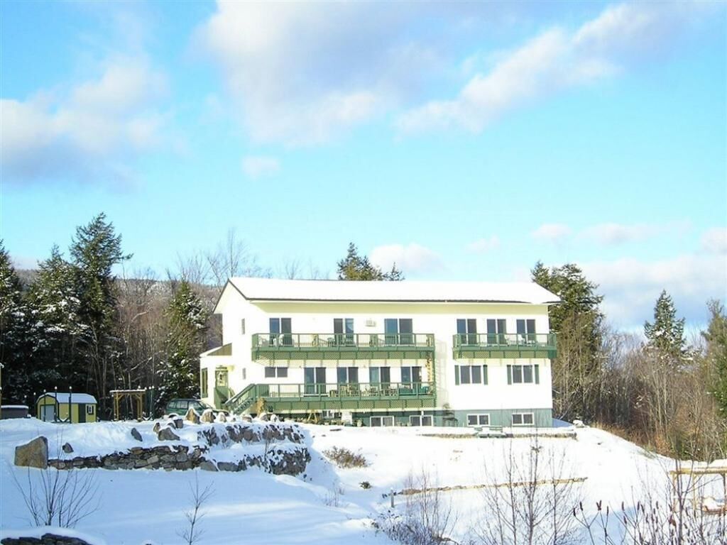 A multi-story building with a flat roof, surrounded by snow and trees.