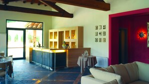 Amplia sala de estar con techo alto, cocina con armarios de madera, comedor con mesa y sillas, y pared de acento roja con detalles decorativos.
