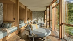 Ein modernes Interieur mit Holzwänden, einer großzügigen, gebogenen Sitzgruppe und großen Fenstern mit Blick auf Grünflächen.