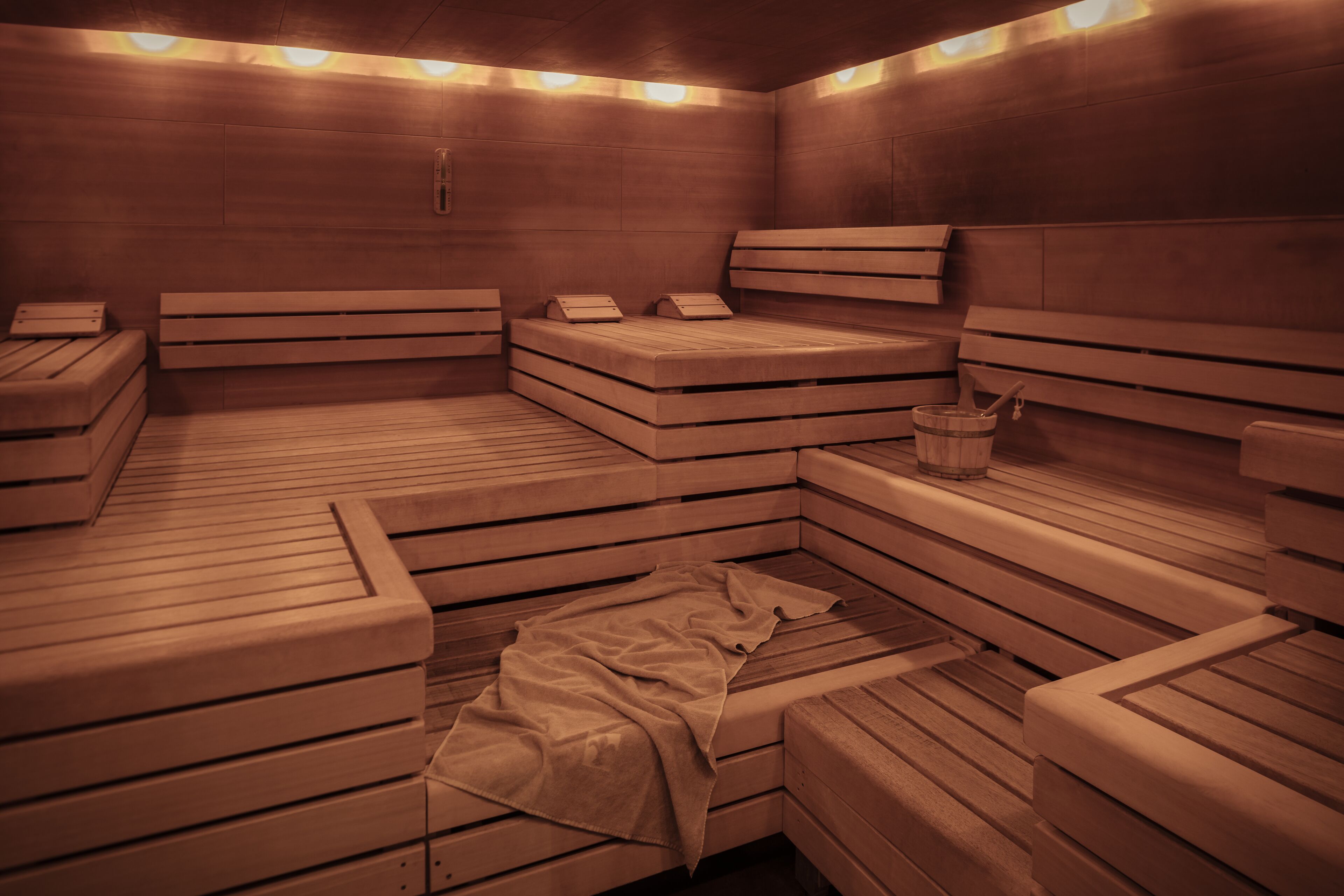 A sauna with multiple benches and a towel on the floor.