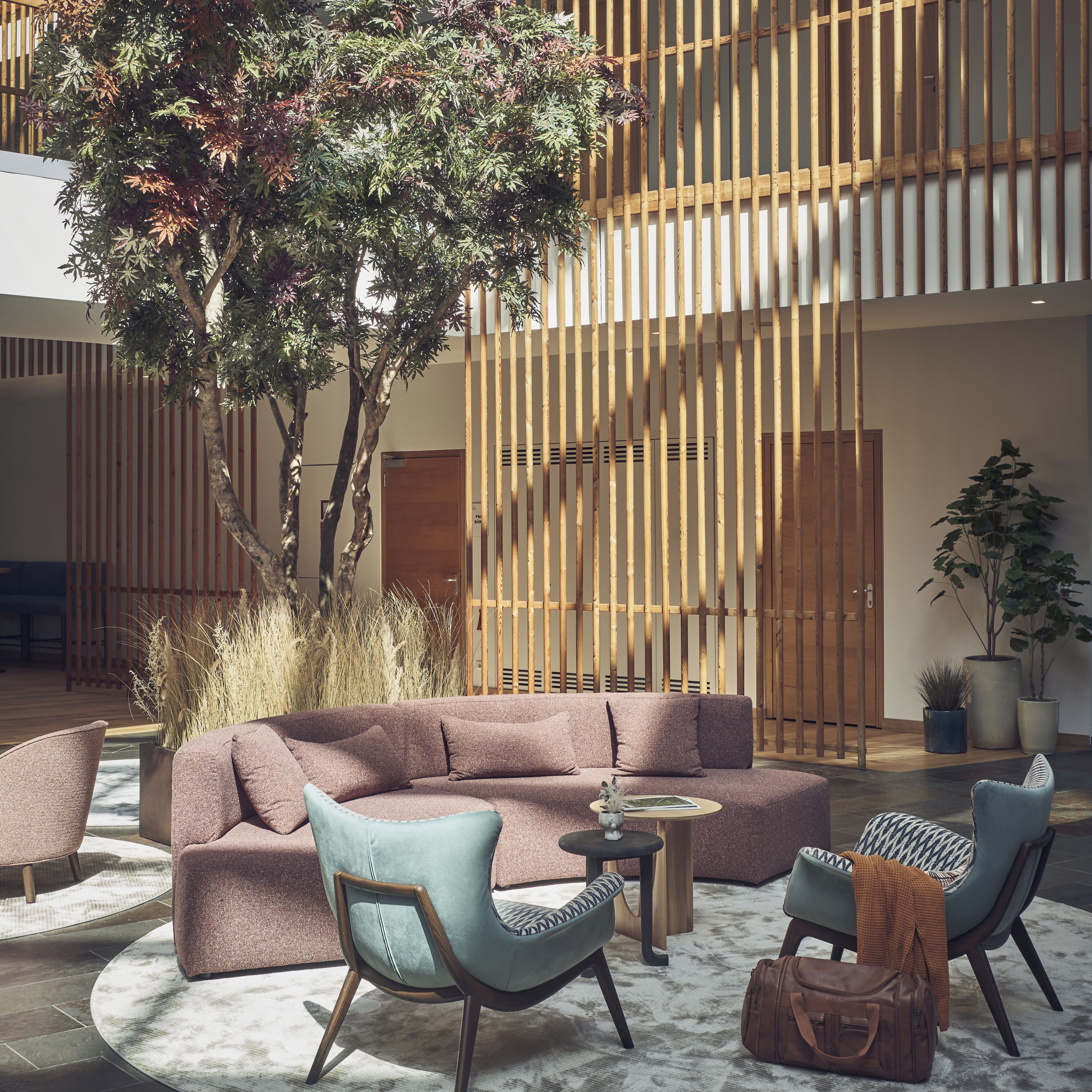 Un interior moderno con un sofá modular, dos sillones, una mesa de centro y una planta en maceta.