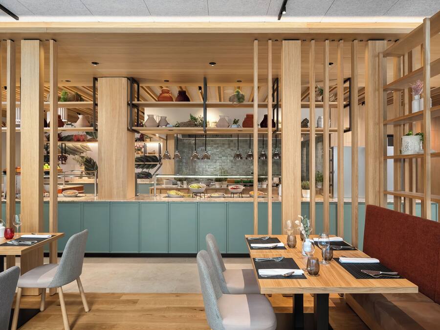 A restaurant with wooden panel dividers, a central kitchen area, and seating arrangements.