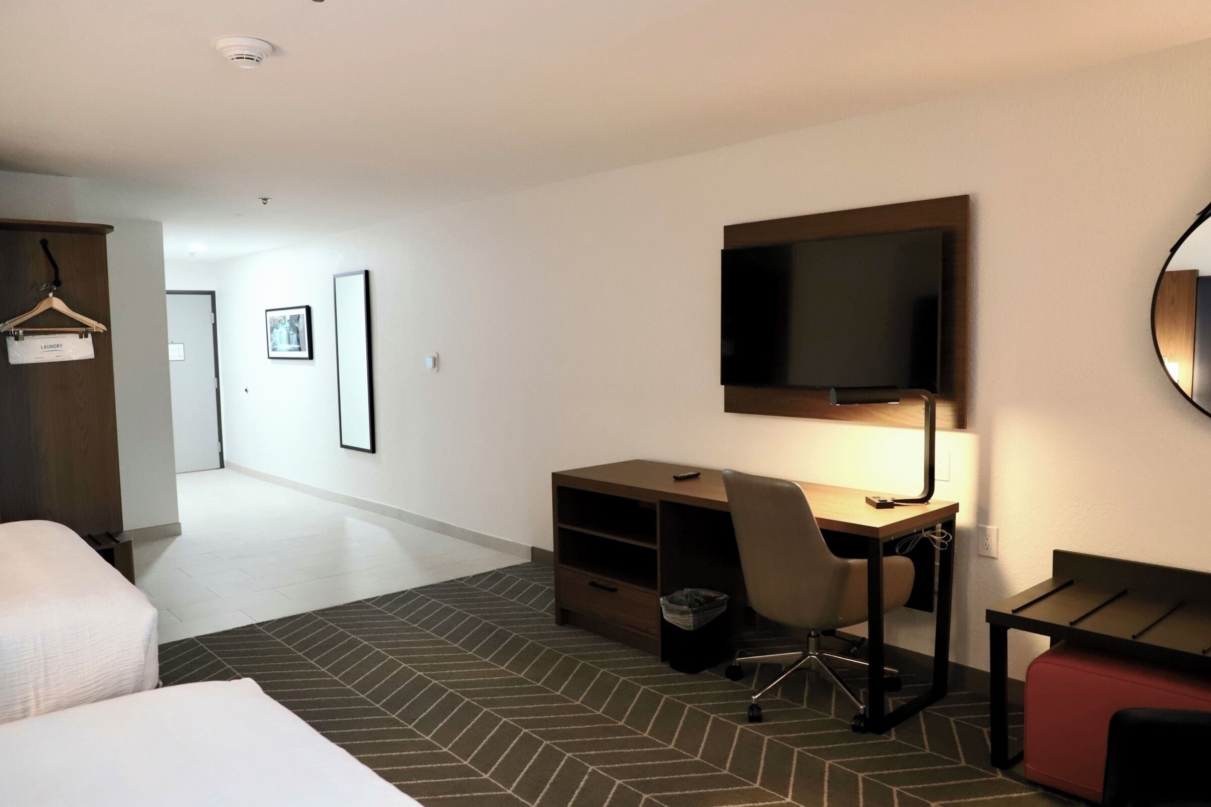 A hotel room with a bed, a desk with a chair, a television, and a wardrobe.