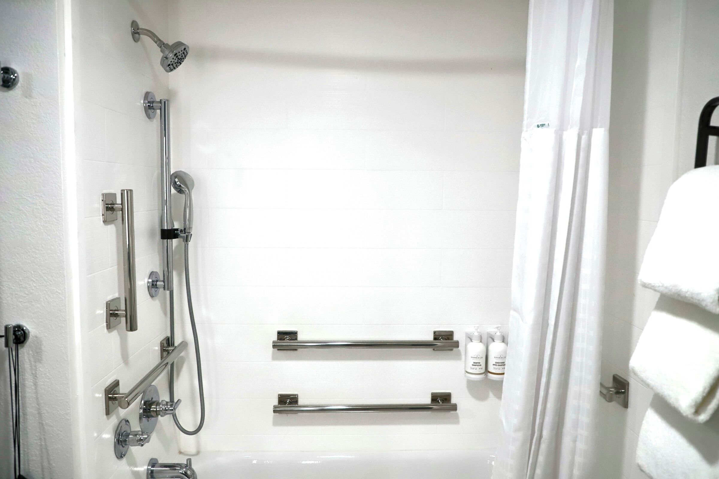 Ein Badezimmer mit Dusche, Toilette und Haltegriffen.