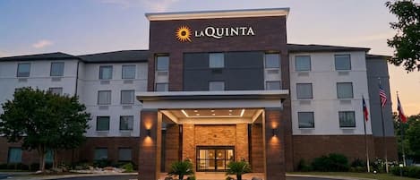 A hotel with a modern facade, a prominent sun logo, and a well-lit entrance.