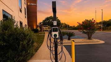 An electric vehicle charging station in a parking lot with a building labeled 'La Quinta' in the background.