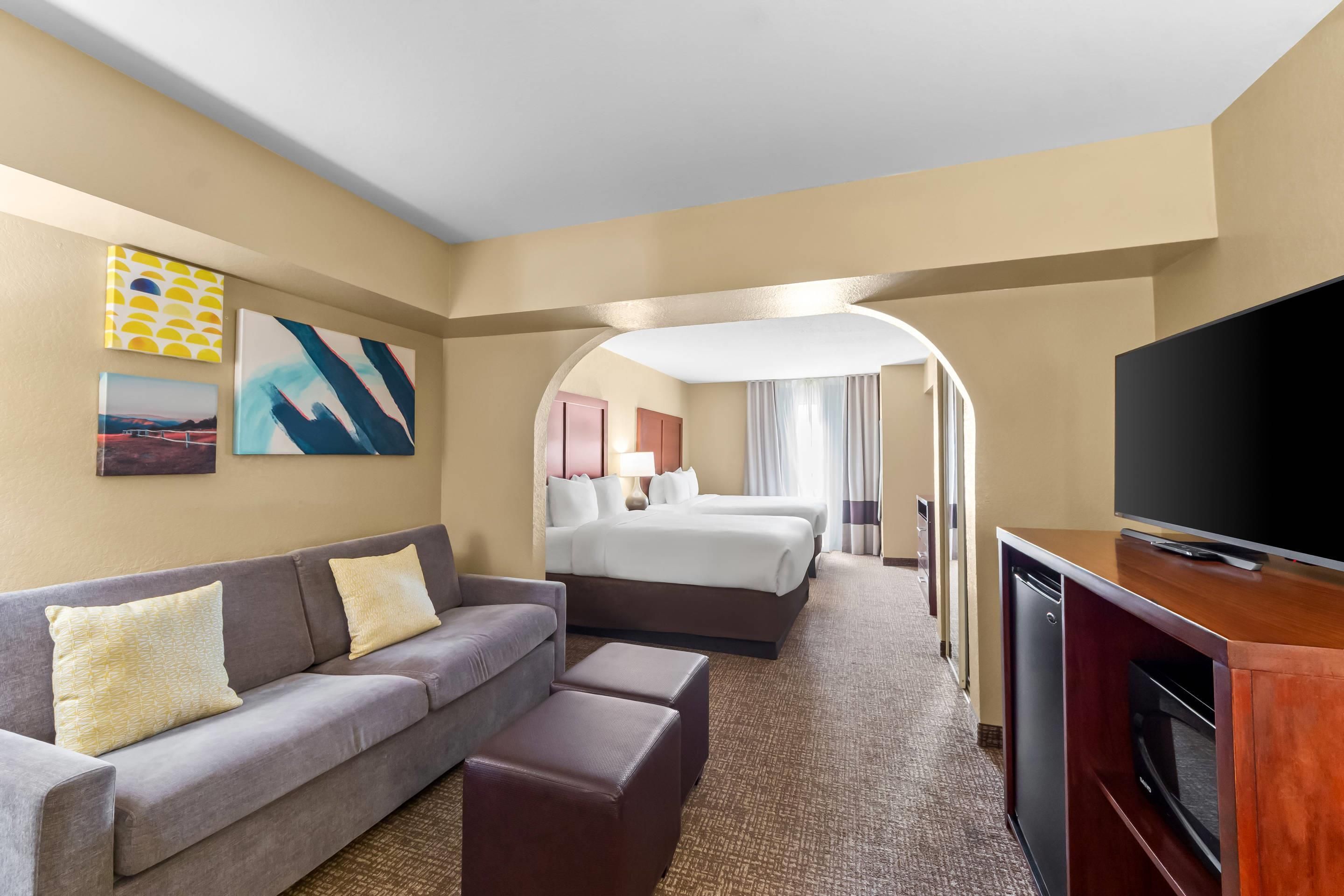 A hotel room with a sofa, a TV, a bed, and a desk.