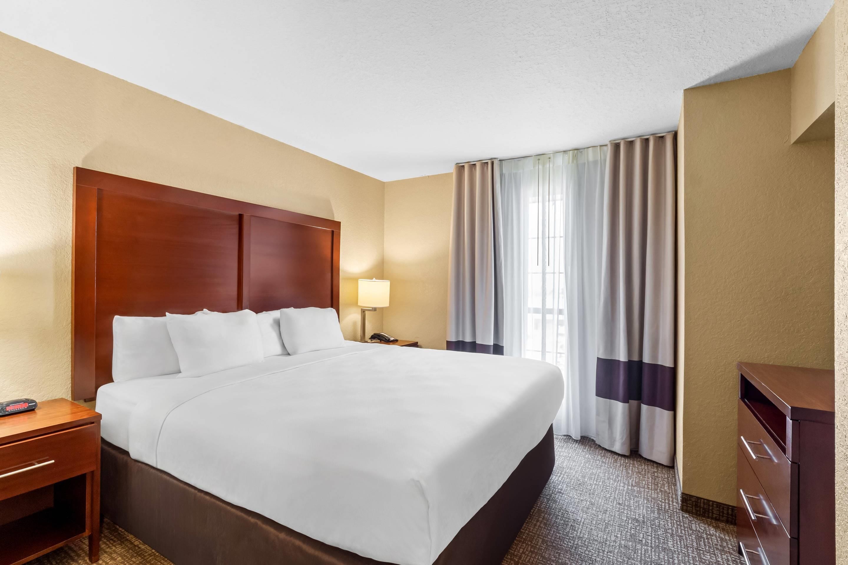 Habitación de hotel con una cama grande, una mesita de noche, una lámpara, un escritorio y un armario.