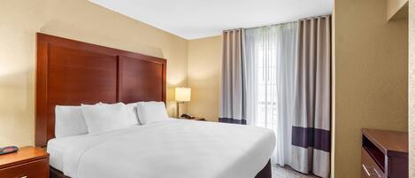 Habitación de hotel con una cama grande, una mesita de noche, una lámpara, un escritorio y un armario.
