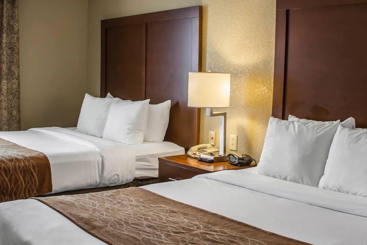 Une chambre d’hôtel avec deux lits, une table de chevet avec une lampe et un téléphone.