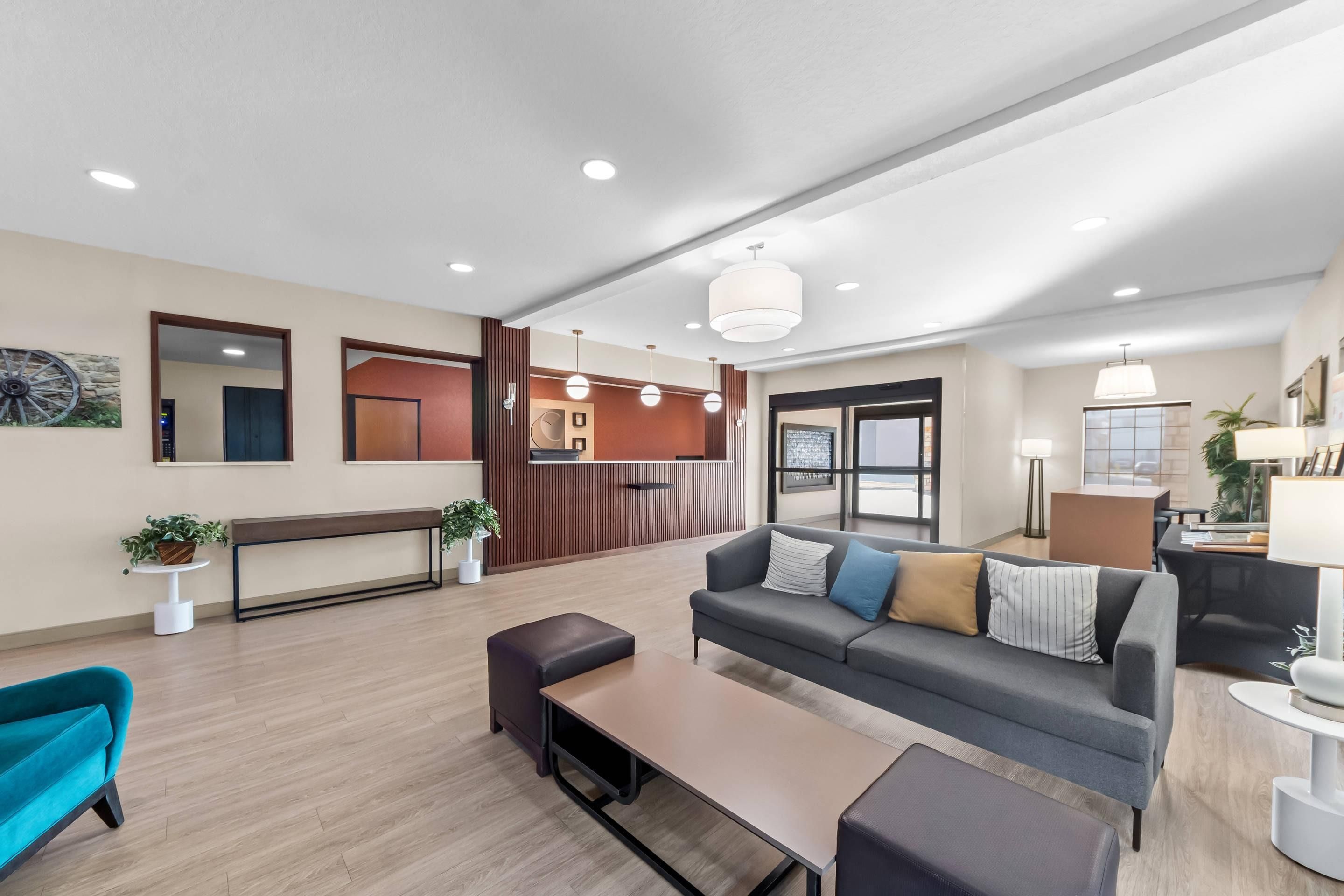 A modern hotel lobby with a reception desk, seating area, and a large window.
