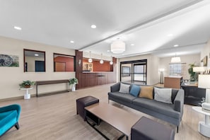 A modern hotel lobby with a reception desk, seating area, and a large window.