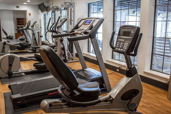 Une salle de sport équipée de tapis de course, de vélos elliptiques et d’un appareil d’aviron.