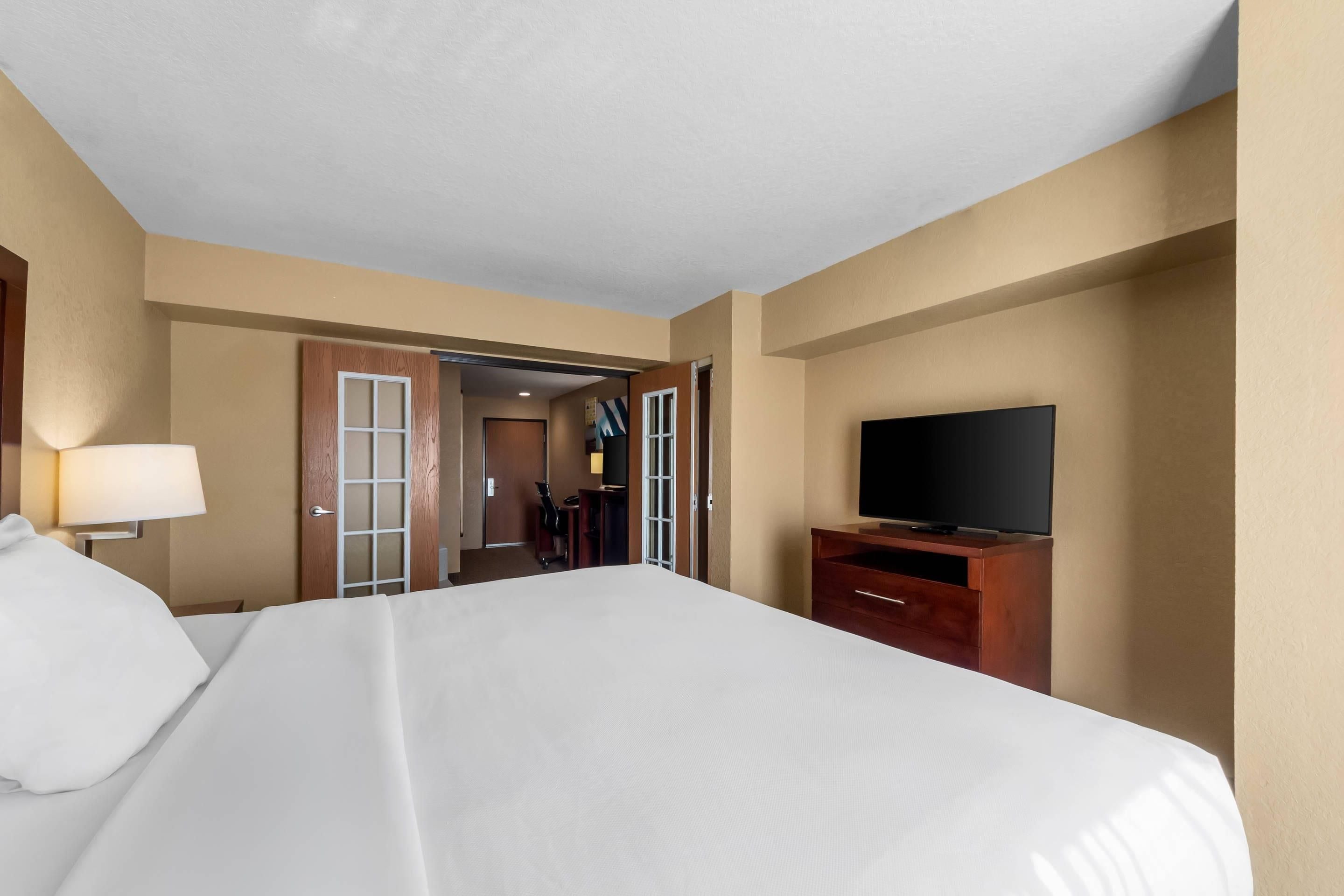 Une chambre d’hôtel avec un grand lit, une télévision et un bureau avec une chaise.