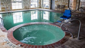 An indoor swimming pool with a brick border, a blue chair, and a sign indicating a depth of 3 feet 6 inches.
