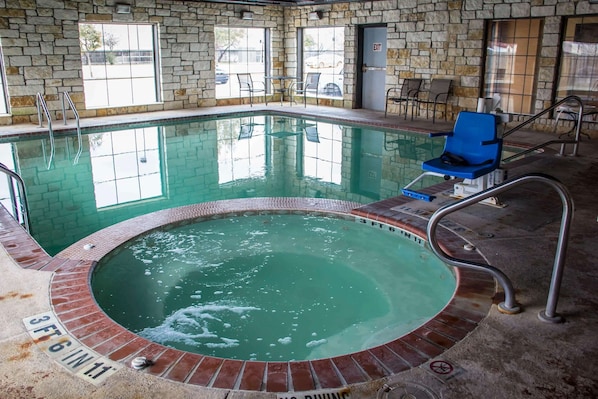 An indoor swimming pool with a brick border, a blue chair, and a sign indicating a depth of 3 feet 6 inches.