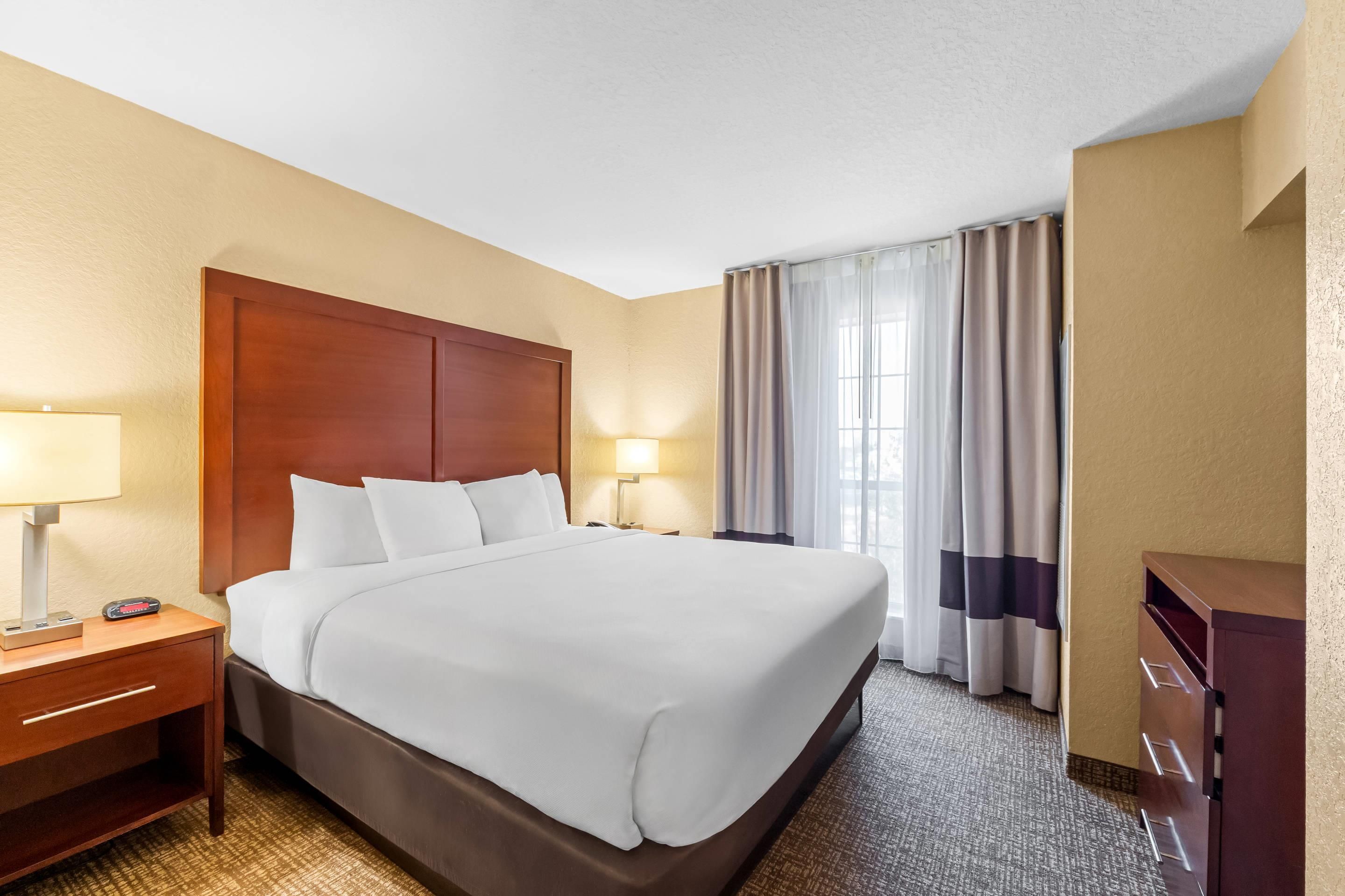 A hotel room with a large bed, bedside tables, a desk, and a wardrobe.