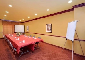 Una sala de conferencias con una larga mesa, sillas, una pizarra y un atril para rotafolio.