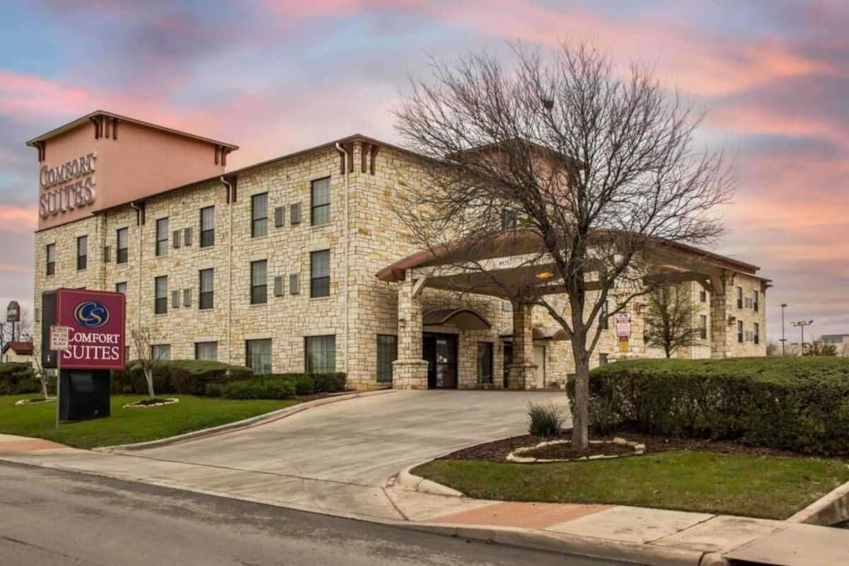Un hotel Comfort Suites con facciata in pietra, ingresso coperto e parcheggio.
