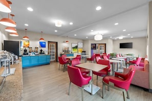A modern cafe with red chairs, a blue counter, and a TV on the wall.