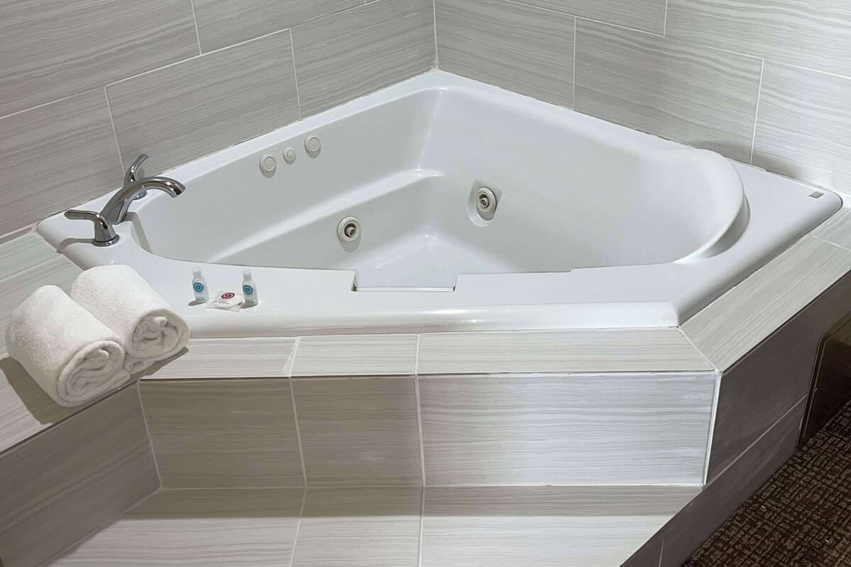 Un bagno moderno con una vasca freestanding, un portascopevoli con asciugamani e una piccola bottiglia di shampoo.