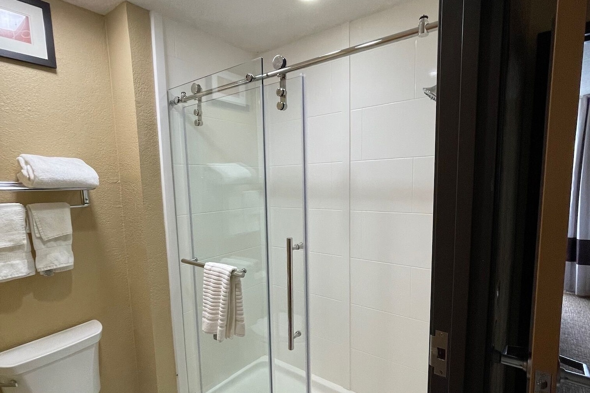 Un baño moderno con ducha de vidrio, inodoro y un toallero con varias toallas.