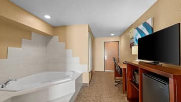 Ein Badezimmer im Hotel mit einer Badewanne, einer Dusche, einer Toilette und einem Fernseher auf einer Holzkabine.