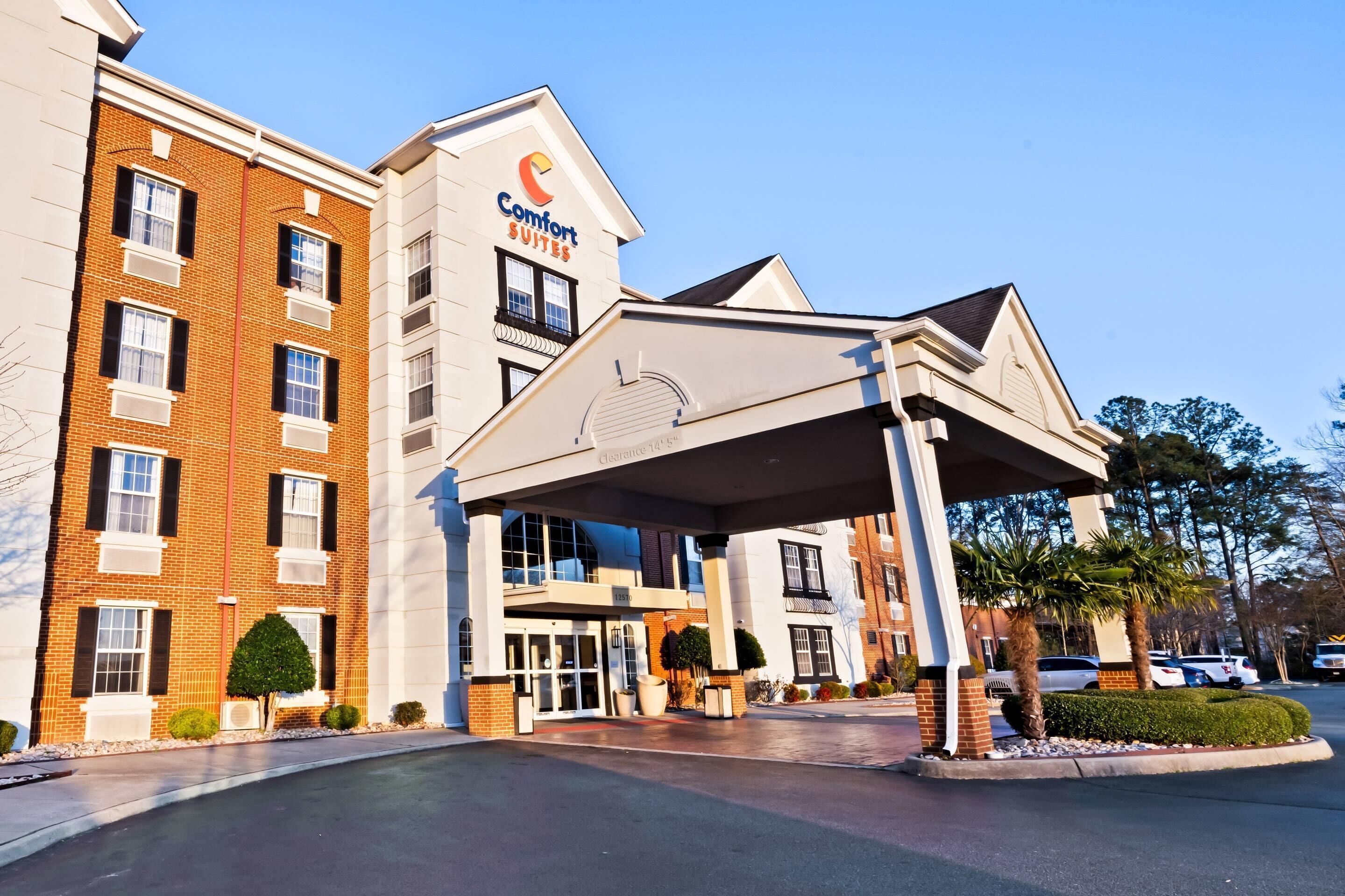 A hotel with a brick facade, a covered entrance, and a sign for 'Comfort Suites.'
