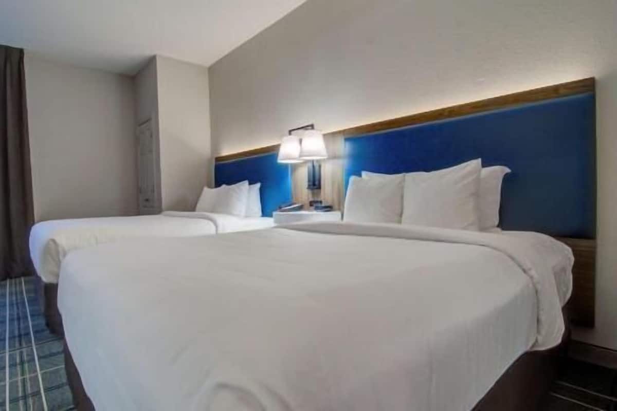 Een hotelkamer met twee bedden, een nachtkastje met een lamp en een blauwe accentmuur.