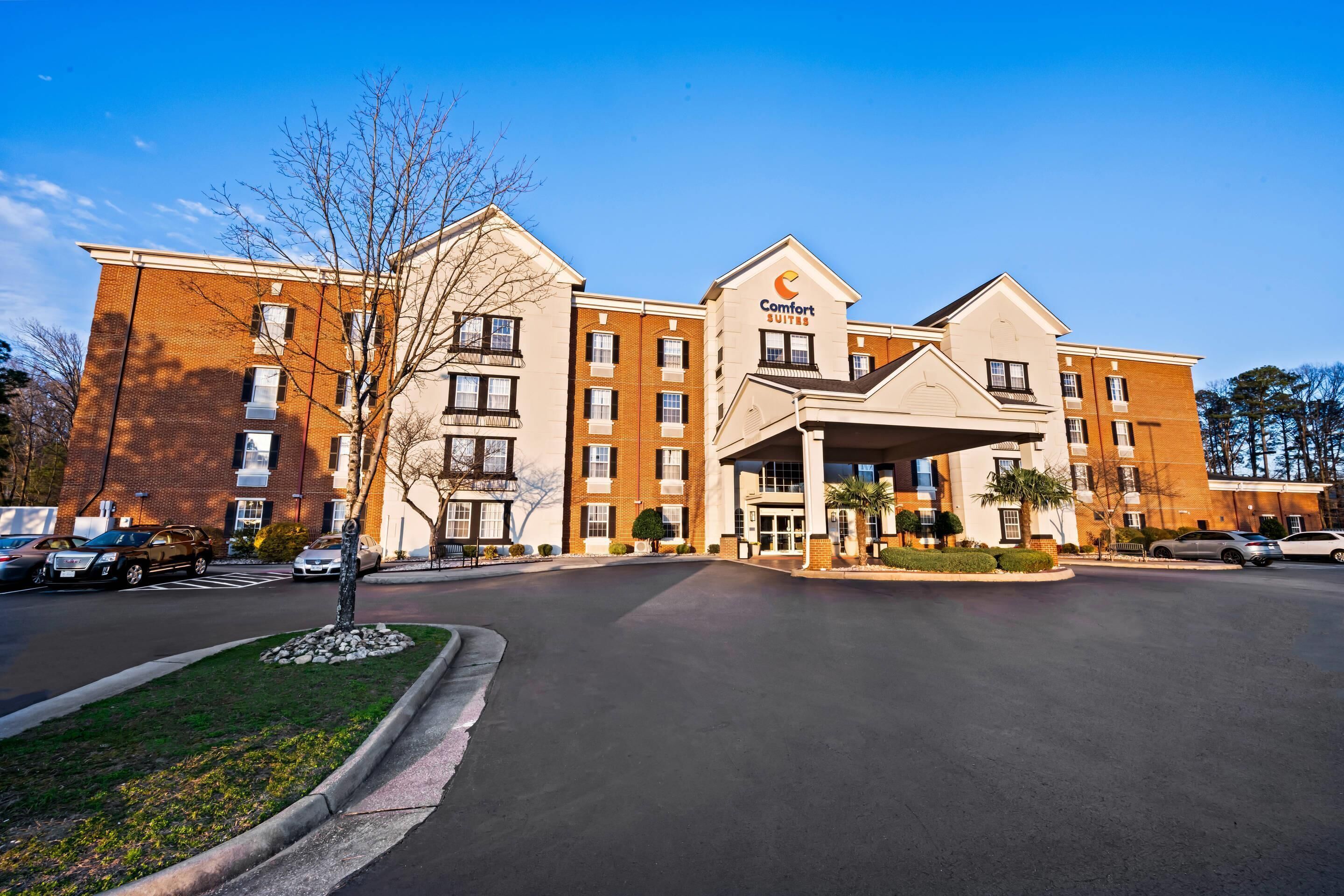 A hotel with a brick facade, a covered entrance, and a parking lot.