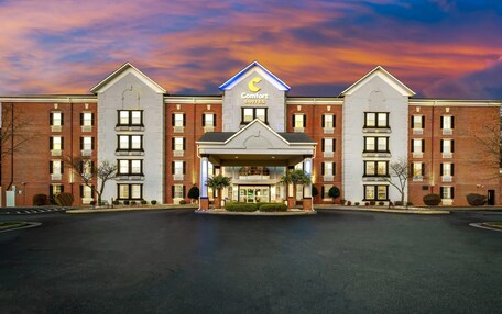 A Comfort Suites hotel with a central entrance, brick exterior, and a distinctive crescent moon logo.