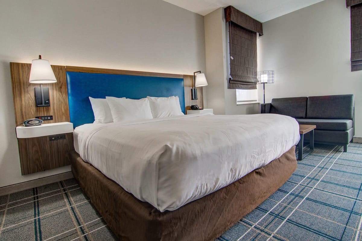 Een hotelkamer met een groot bed, nachtkastjes, een bureau, een stoel en een bank.