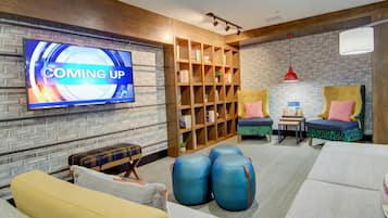 Una sala de estar moderna con televisor, estanterías, sofás y una lámpara colgante roja.