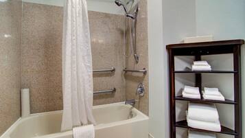 A bathroom with a bathtub, shower, and a shelf with towels.