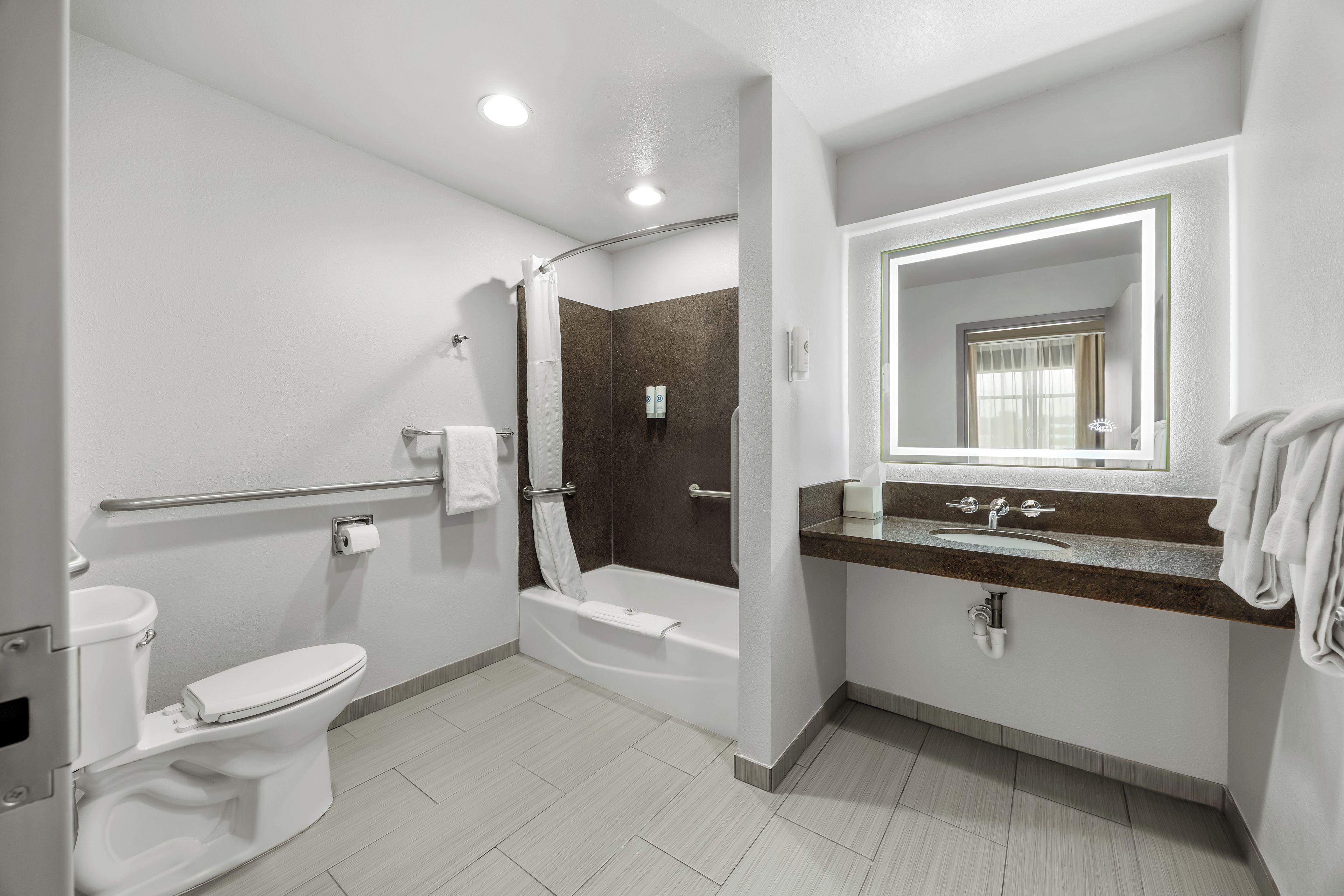 A modern bathroom with a toilet, shower, and sink.