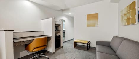 A modern office space with a desk, chair, and a grey sofa.
