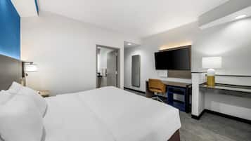 A hotel room with a bed, desk, chair, TV, and a mirror.