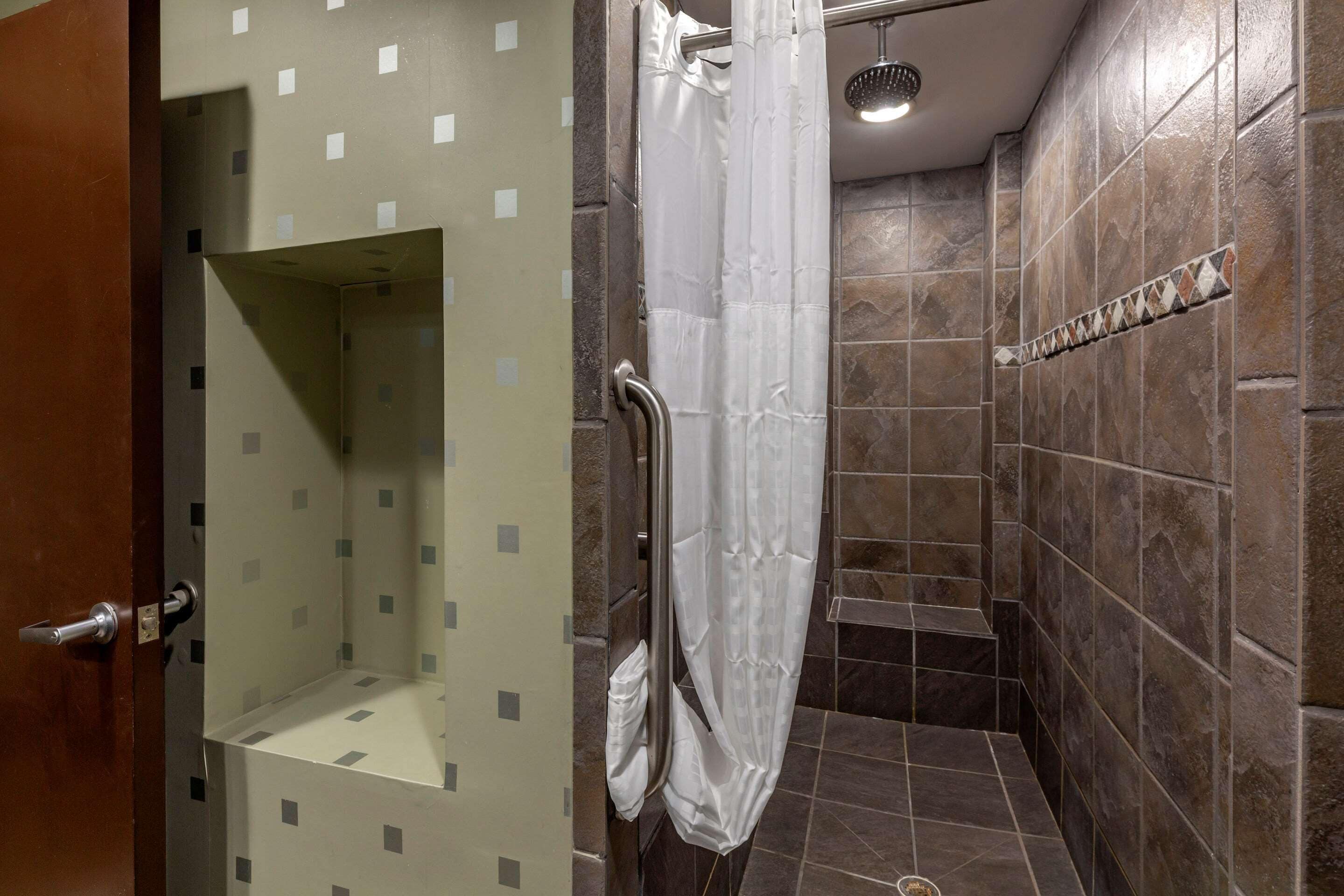 A bathroom with a shower, tiled walls, and a door.