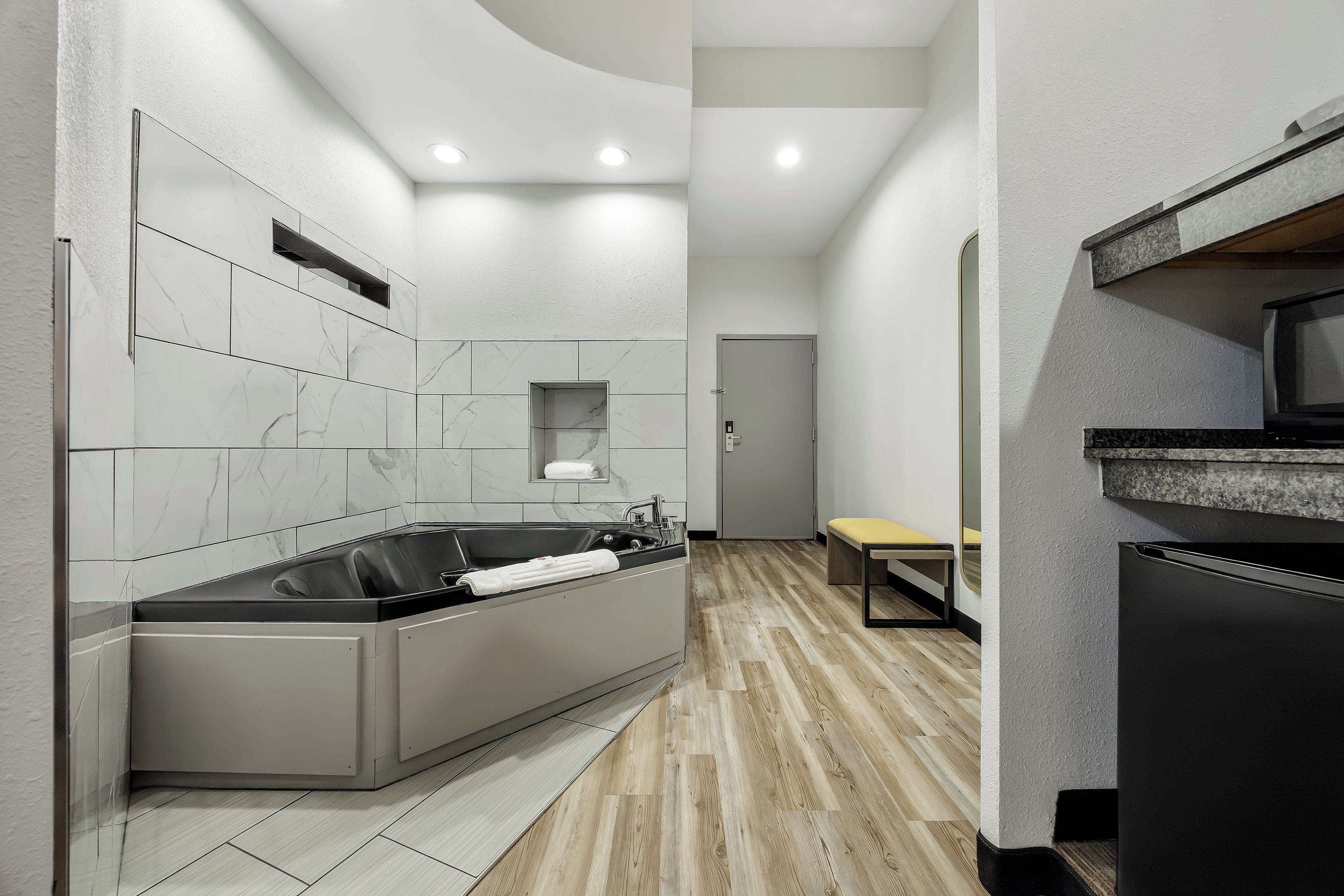 Un baño moderno con bañera empotrada, tocador con espejo y suelo de madera.