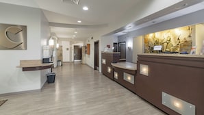 A hotel reception area with a stone wall backdrop, a reception desk, and a hallway leading to other rooms.