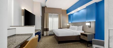 A hotel room with a bed, a desk, a chair, a television, and a bathroom.