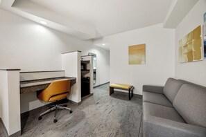 Un espace de bureau moderne comprenant un bureau, un fauteuil de bureau, un canapé et une petite table.
